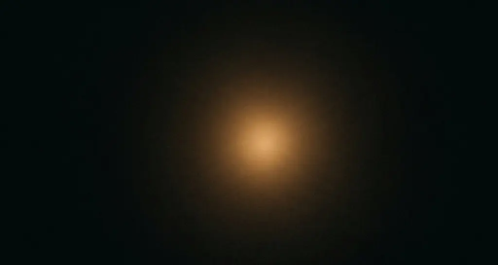 A warm amber glow emerging from complete darkness, evoking the first moment of awareness