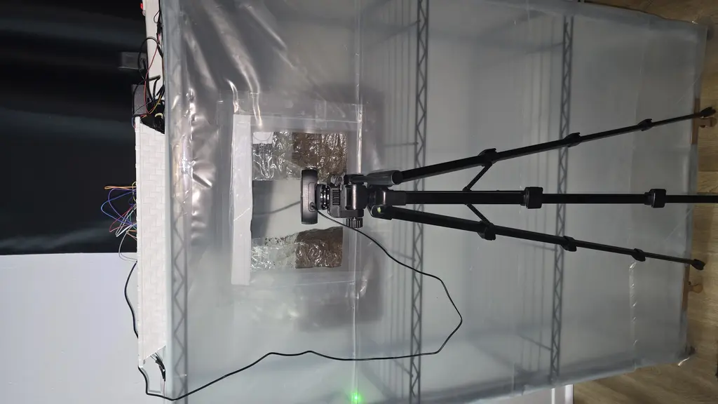 Prototype grow tent — vapor-sealed shelving unit with viewing window and camera on tripod